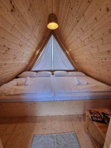 a bed in a wooden room with a large window at Glamp Pr Kuzuc in Cerklje na Gorenjskem