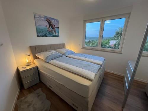 a bed in a bedroom with two windows at Marina Penthouse in Punat