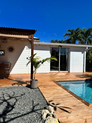 a house with a swimming pool on a wooden deck at Le Frangipanier Cozy Bungalow in Le Moule