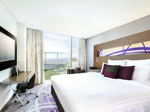 a hotel room with a large bed and a television at Novotel Ambassador Suwon in Suwon