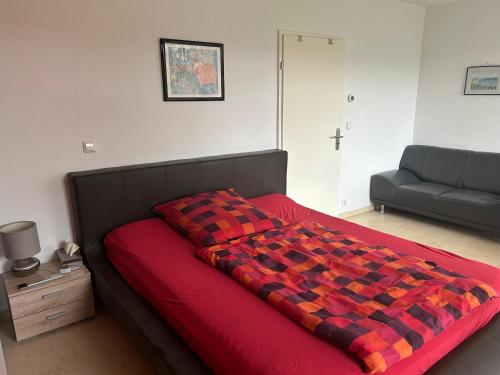 a bedroom with a red bed and a couch at Garten Wohnung in Singen