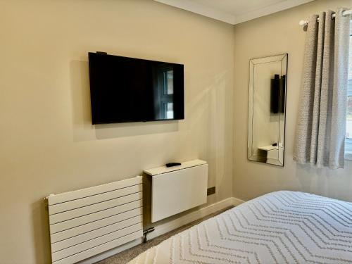 a bedroom with a bed and a tv on the wall at Holly Lodge - 2 x Kingsize bedrooms with private entrance and free parking-new shower room in Oban