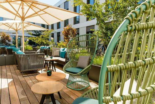 a patio with chairs and tables and an umbrella at Motel One München-Messe in Munich