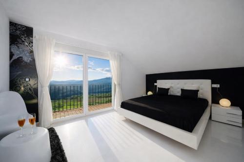 a white bedroom with a bed and a large window at Casa Rural La Esencia in Araguás