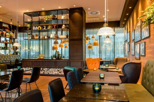 a restaurant with tables and chairs and a bar at Motel One Salzburg-Süd in Salzburg