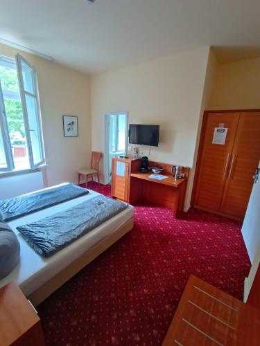 a bedroom with a bed and a desk and a television at Die Villa Hotel in Leverkusen