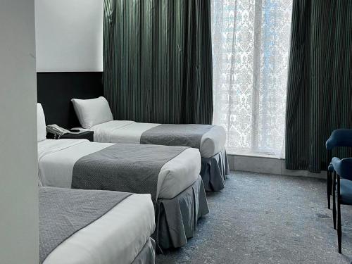 a hotel room with three beds and a window at Montana Golden Hotel in Mecca