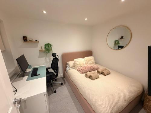 a bedroom with a bed with a desk and a mirror at Adrian Cottage in Abbots Langley