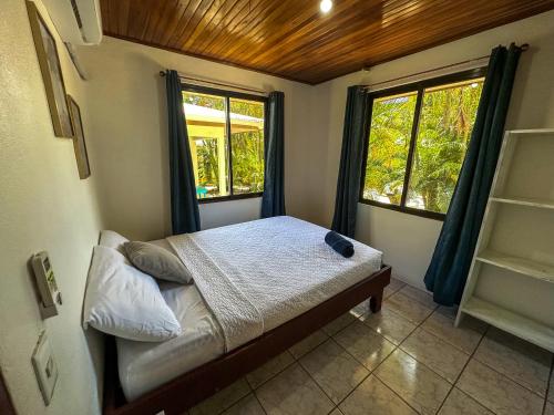 a small bedroom with a bed and two windows at Koba Apartments Santa Teresa in Santa Teresa Beach