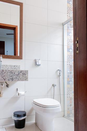 a white bathroom with a toilet and a mirror at Hotel Cheffer in Pôrto Ferreira
