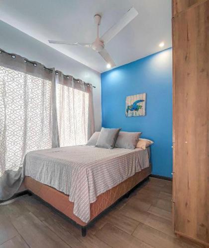 a bedroom with a bed with a blue wall at Casa Solana in Puntarenas