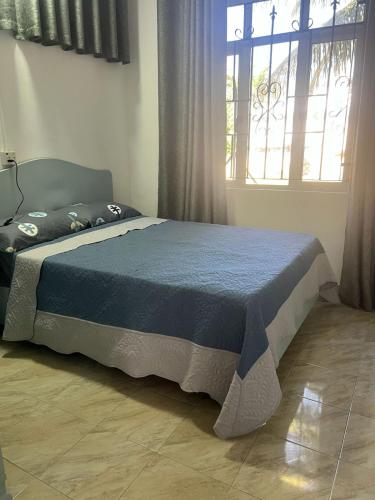 a bedroom with a bed with a blue comforter and a window at TecTec 2 Appartment 1 in Pereybere