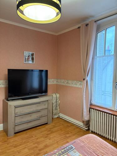 Comme chez vous في Meusnes: غرفة معيشة بها تلفزيون بشاشة مسطحة موضوع على خزانة ملابس