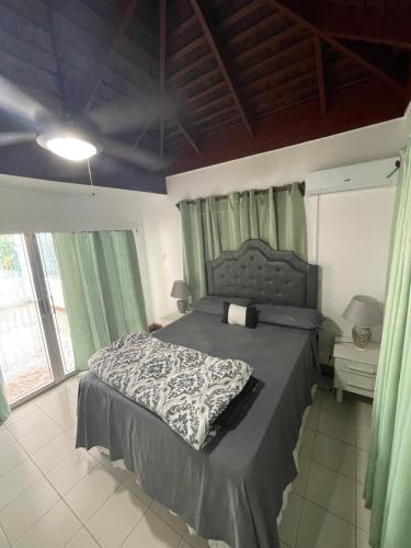 a bedroom with a large bed with green curtains at Peaceful Private Home With Exclusive Swimming Pool in Montego Bay