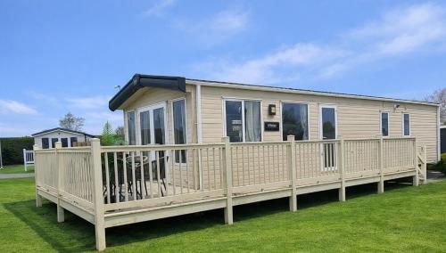 a mobile home with a porch and a fence at Southview Holiday park in Winthorpe