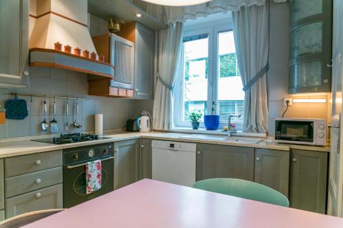 Tomas's apartment في ليوبليانا: مطبخ مع طاولة وردية وبعض النوافذ