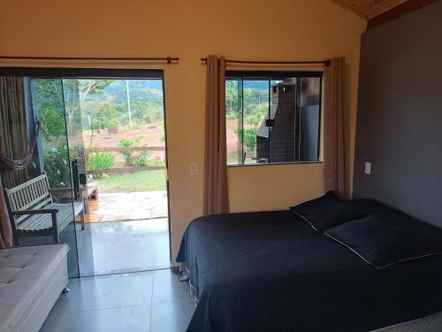 a bedroom with a bed and a sliding glass door at Refúgio São Tomé in São Thomé das Letras