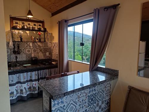 a kitchen with a glass counter and a window at Refúgio São Tomé in São Thomé das Letras