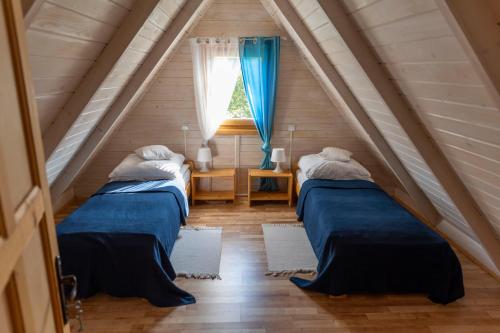 two beds in a attic room with a window at Słoneczna Przystań in Sasino