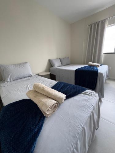 two beds in a room with towels on them at Refúgio Vila Mar Apto in Imbituba