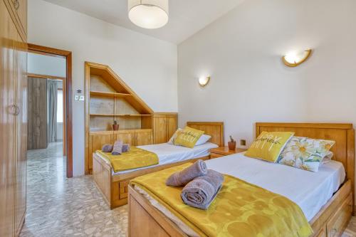 a bedroom with two beds with yellow sheets at Luxurious Villa with pool in Il-Mielaħ