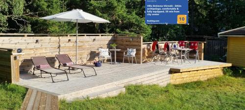 a wooden deck with two chairs and an umbrella at Villa Strömma Värmdö - Scandinavian Living - Sea, Nature and Comfort 35 min to Stockholm in Värmdö