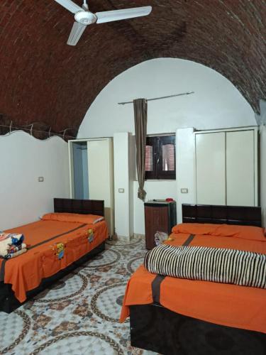 a room with two beds with orange sheets at Rooma ka Guest House in Aswan