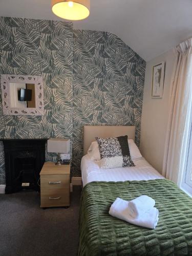 a bedroom with a bed with towels on it at Glascoed Guest House in Llandudno