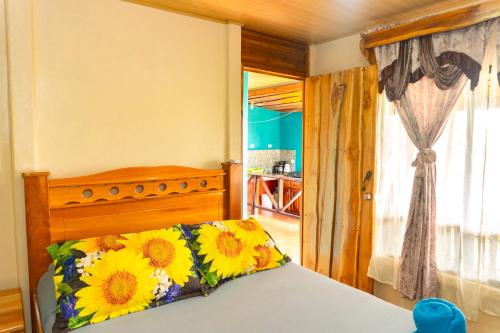 a bedroom with a bed with a flower pillow on it at Hotel Casa Gitana Corcovado Tour operador in Drake