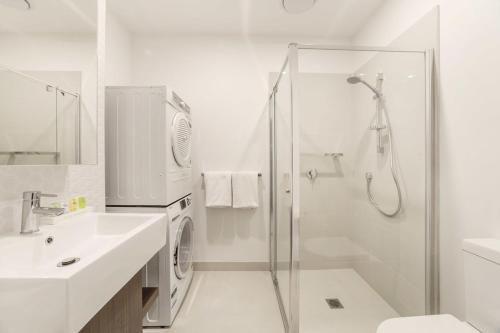 a white bathroom with a shower and a sink at Whitehorse Apartments Hotel in Box Hill