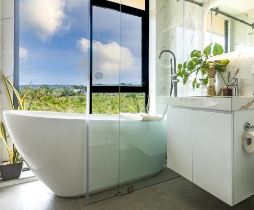a white bathroom with a tub and a window at Villa 360 in Calaca