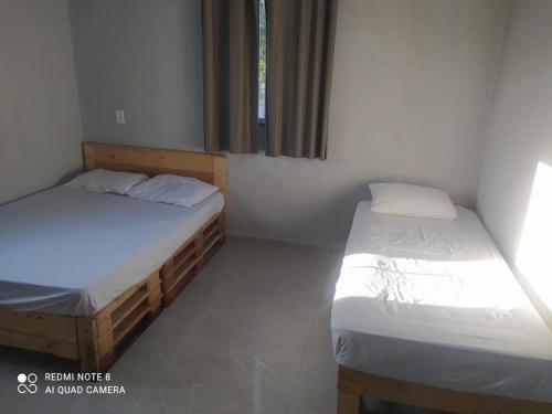 two twin beds in a room with a window at PÔR Do SOL BEACH in Marataizes