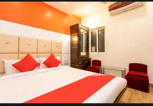 a bedroom with a bed and two red chairs at Samarth guest house in Indore