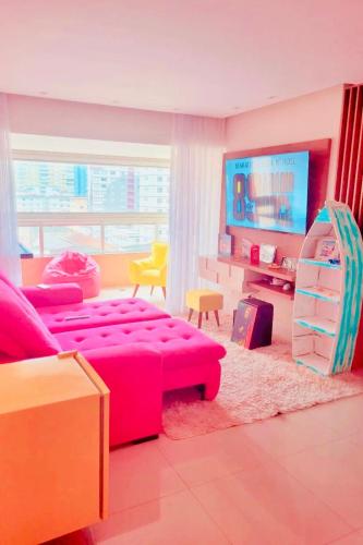 a living room with a pink couch and a tv at Ilha Salinas Canto do Forte in Praia Grande