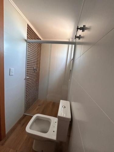 a small bathroom with a toilet and a shower at Ilha Salinas Canto do Forte in Praia Grande