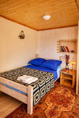 a bedroom with a bed with blue sheets and a wooden ceiling at The Secret Garden House in Ijevan