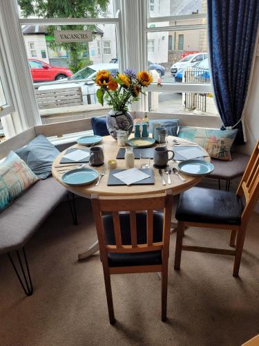 a table with chairs and a vase of flowers on it at Glascoed Guest House in Llandudno