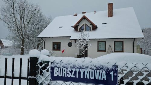 a house covered in snow with a sign on a fence at Bursztynowa 1 in Sztutowo