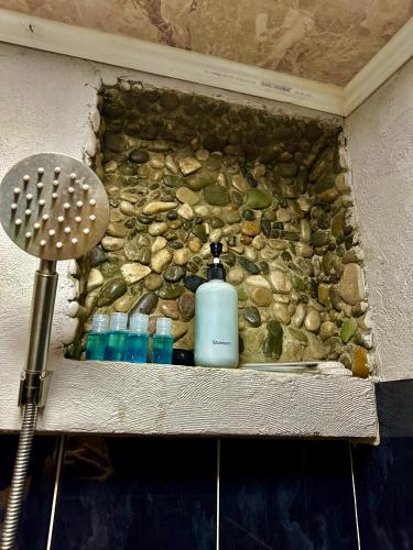 a shower stall with a bottle of soap and rocks at The Secret Garden House in Ijevan