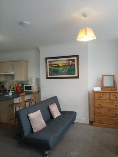 a living room with a blue couch and a kitchen at Lovely 1-bedroom flat within minutes from the beach! in Bexhill