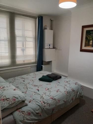 a bedroom with a bed with a floral comforter at Lovely 1-bedroom flat within minutes from the beach! in Bexhill