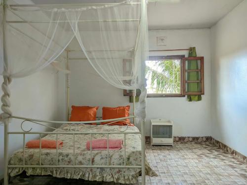 a bedroom with a bed with orange pillows and a window at Villa Étage Z Irma in Antsiranana