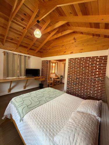 a large bed in a room with a wooden ceiling at Cabañas Tlaxomolco in Tepoztlán