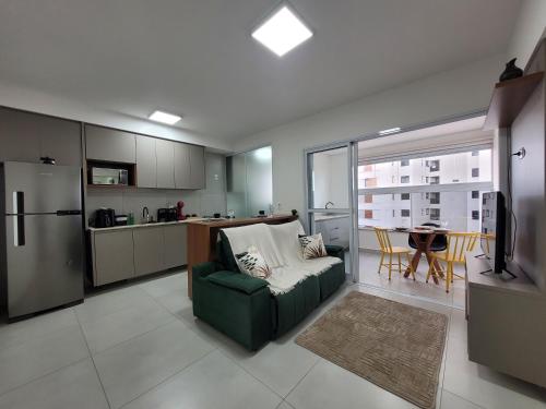 a living room with a green couch and a kitchen at Lavit 92 - Conforto, estilo e lazer com piscina e academia in Bauru