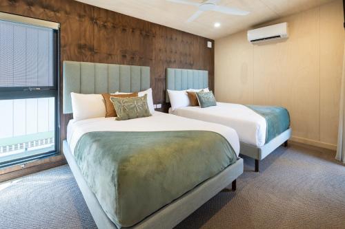 two beds in a room with two windows at Ashmore Palms Holiday Village in Gold Coast