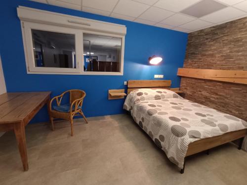 a bedroom with blue walls and a bed and a desk at Appartement original tout confort in Condamine