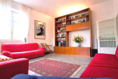 a living room with red furniture and a book shelf at Cappuccini Florence your easy stay close to the center in Florence