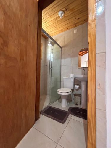 a bathroom with a toilet and a glass shower at Mini Fazenda Park in Santana do Livramento