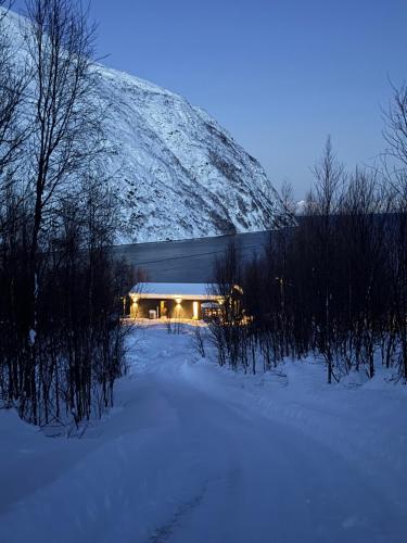 a building in the snow with a snow covered mountain at Lyngen Alps Inn in Lyngseidet