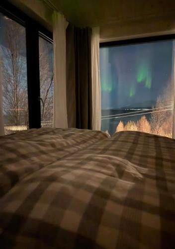 a bedroom with a bed and a window with the aurora at Lyngen Alps Inn in Lyngseidet